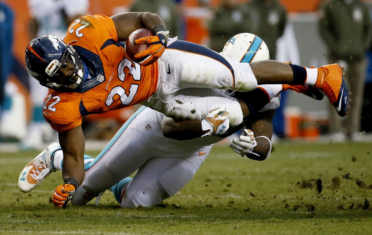 Denver Broncos running back C.J. Anderson is hit by Miami's Randy Starks during the Broncos' 39-36 home victory on Sunday, November 23.