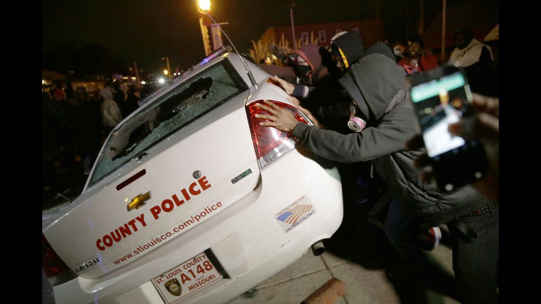 A group of protesters vandalizes a police vehicle in Ferguson on November 24.