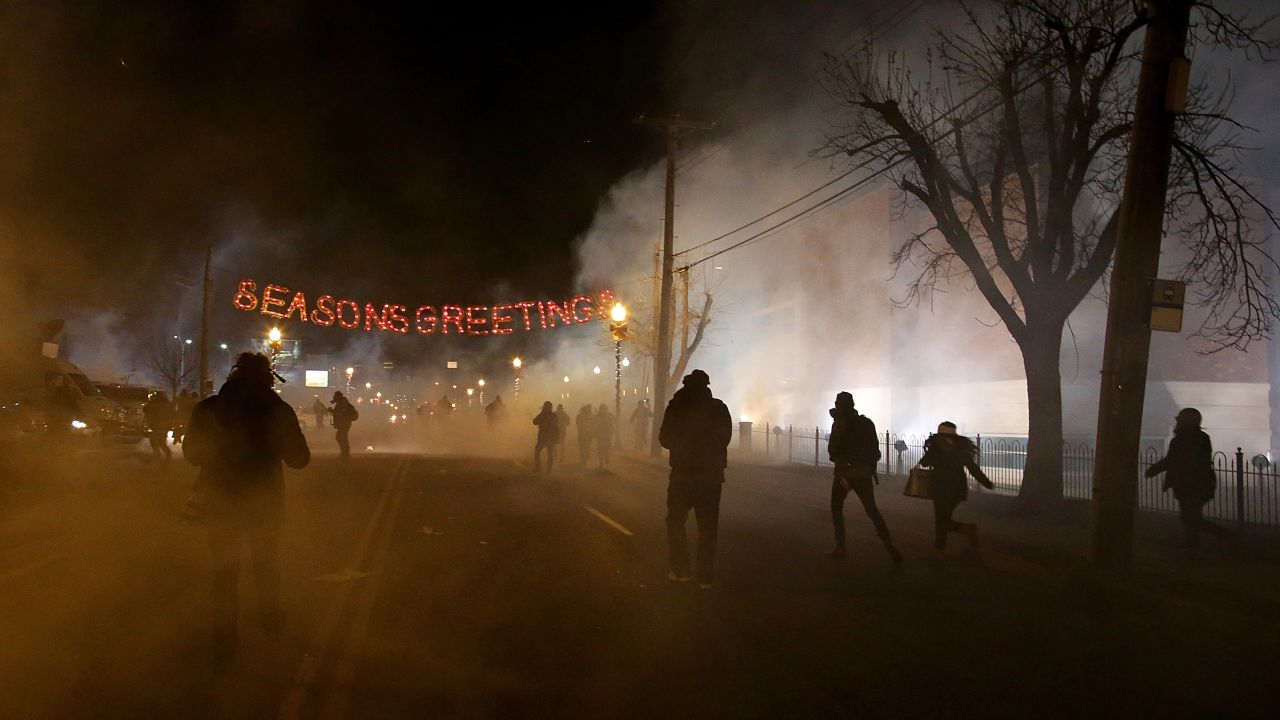 Protesters run away after police deployed tear gas in Ferguson on Monday, November 24.