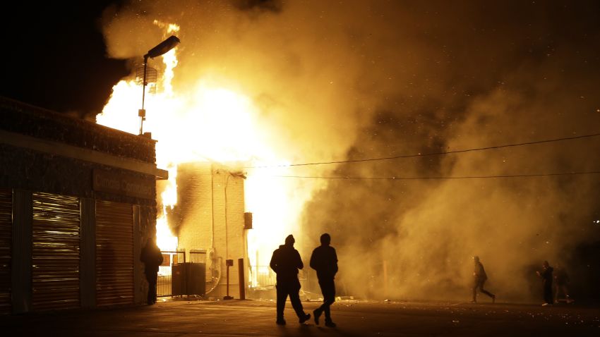 People walk away from a burning storage facility in Ferguson.