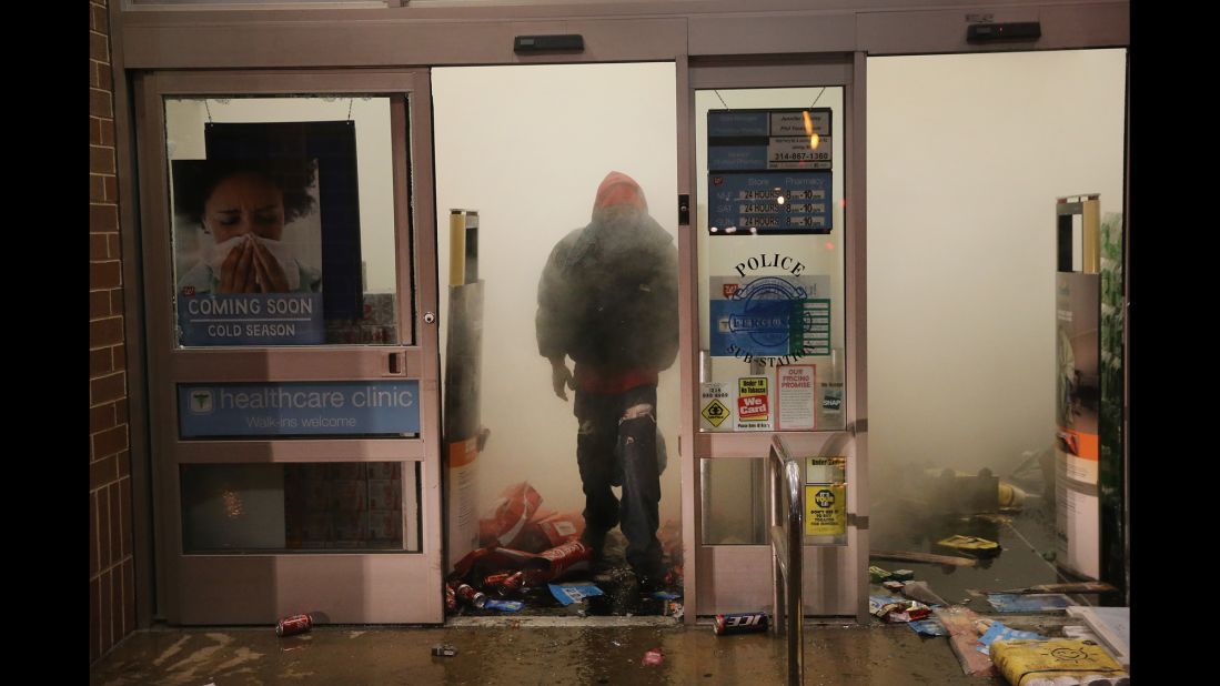 A looter in Ferguson walks out of a burning Walgreens on November 24.