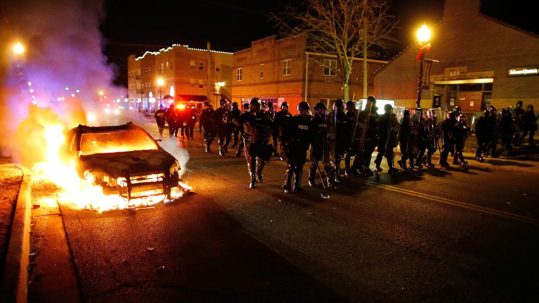 Police in riot gear move past a burning vehicle on November 24.