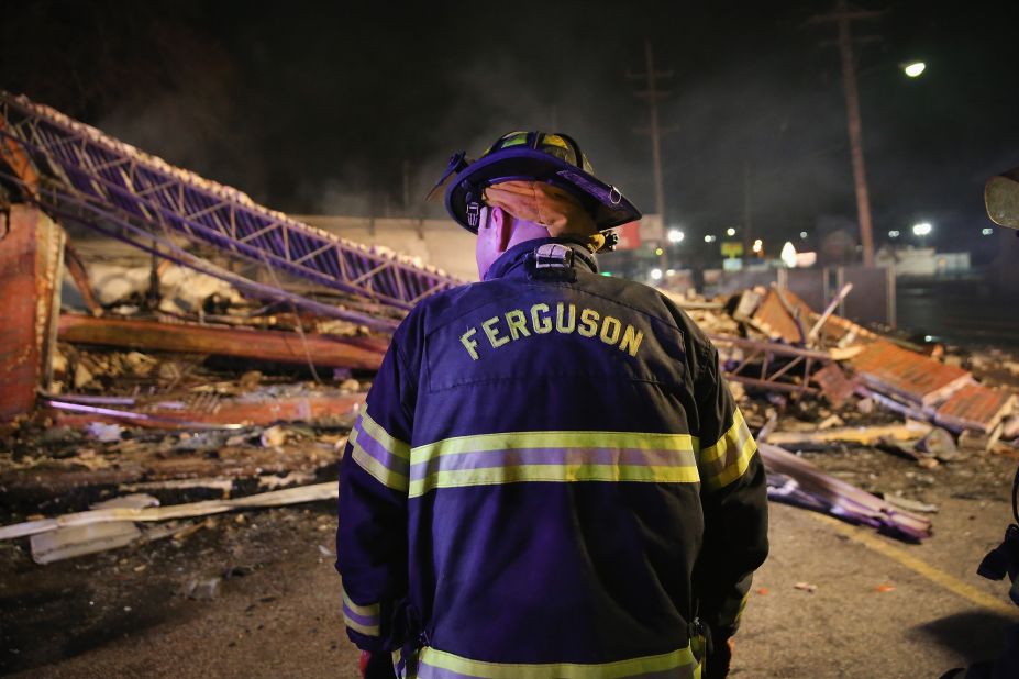 A Ferguson firefighter surveys rubble at a strip mall that was set on fire overnight.