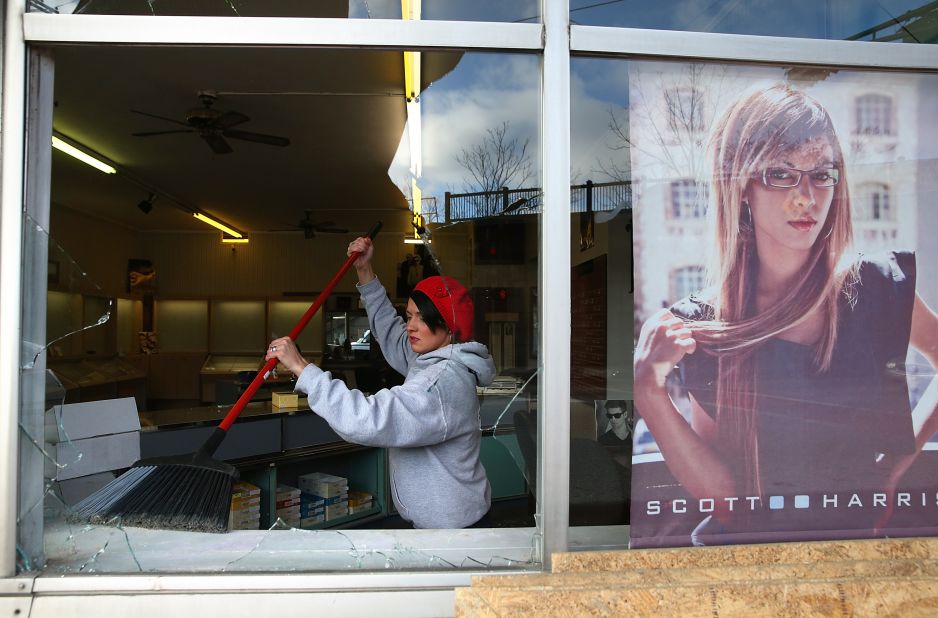 A woman cleans up glass from a business' shattered window on November 25.