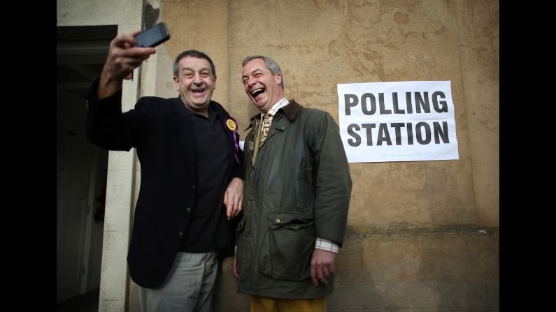 Nigel Farage, leader of the UK Independence Party, poses for a selfie with party worker Lee Jarvis, left, at a polling station in Rochester, England, on Thursday, November 20.