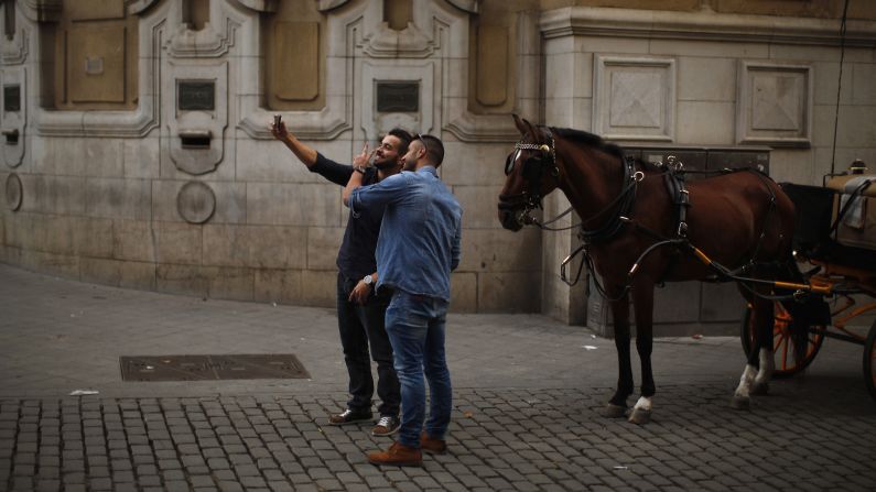 Men take a selfie with a horse in the downtown area of Seville, Spain, on Friday, November 21.