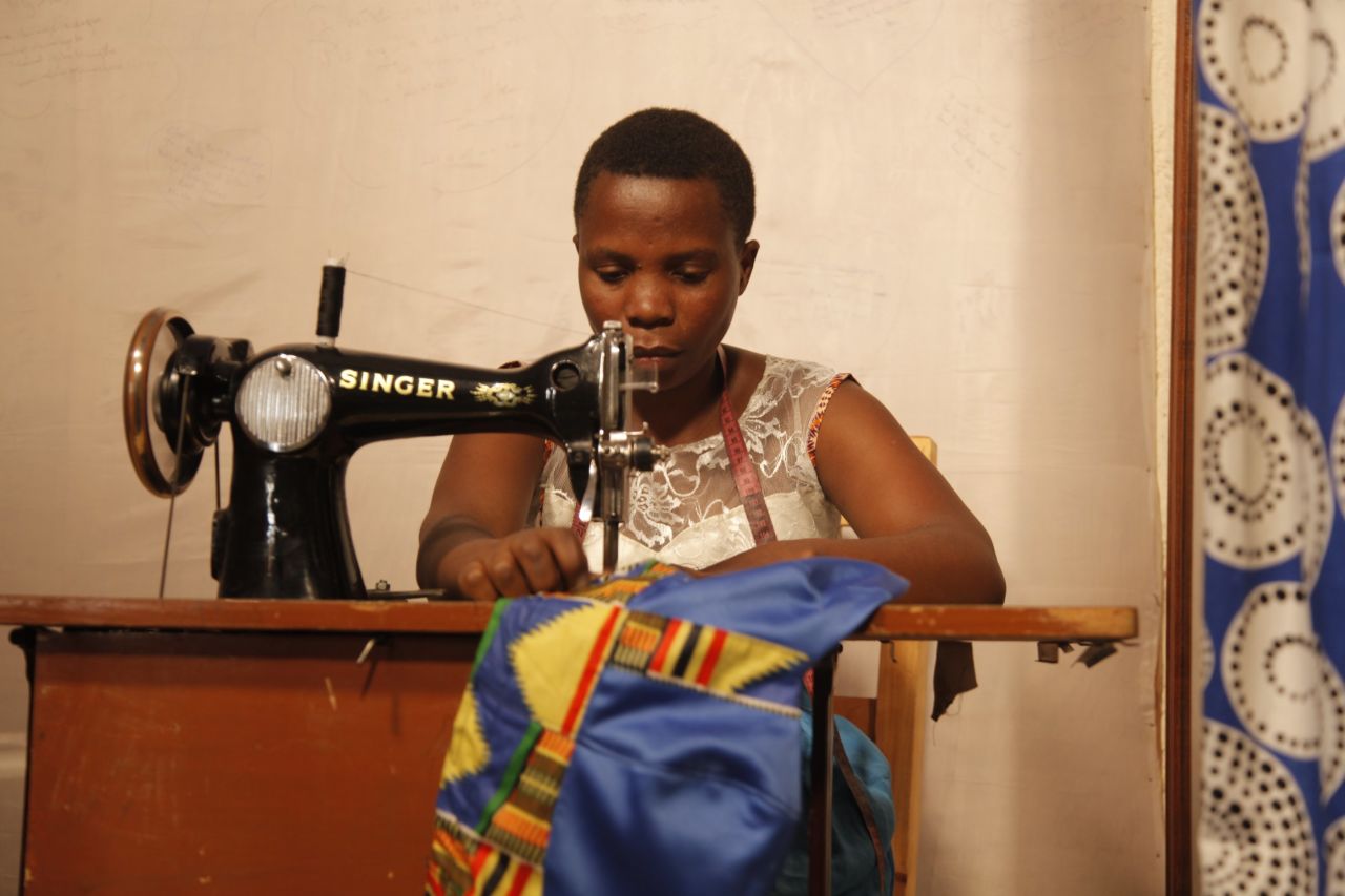 Mama Ngawerie helps Mbabazi tailor clothes to customers' exact needs in a private area of the shop. 