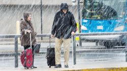 Airline passengers at Dulles International Airport outside Washington, DC,  in Virginia, arrive to snow showers on the busiest travel day of the year November 26, 2014. Hundreds of flights were cancelled or delayed Wednesday in the US northeast as a winter storm delivered freezing rain and snow ahead of the Thanksgiving holiday, one of the year's biggest travel weekends. A wintry mix was falling in Boston, Philadelphia, New York and Washington, according to the National Weather Service, which forecast "havoc" for travelers along the east coast from the Carolinas up through New England.    AFP Photo/Paul J. Richards        (Photo credit should read PAUL J. RICHARDS/AFP/Getty Images)
