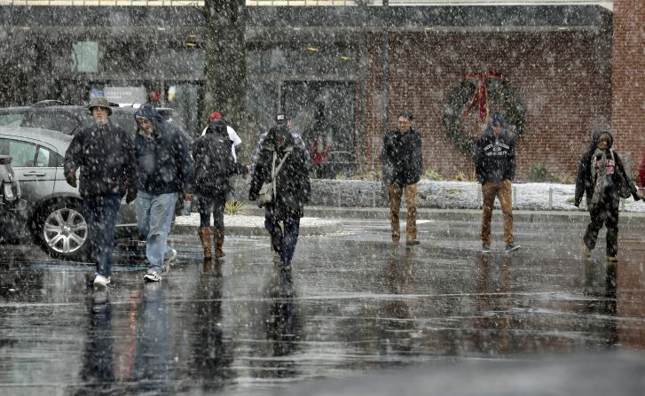 People walk through falling snow at a rest stop in Aberdeen, Maryland, on November 26