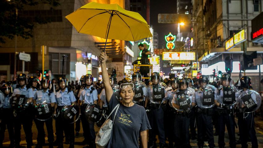 NOVEMBER 25 - HONG KONG: A pro-democracy activist holds a yellow umbrella in front of a police line on a street in Mong Kok district on November 25, 2014 in Hong Kong. Police and authorities have started clearing barricades and tents from the group's protest camp, almost two months after demonstrations began.