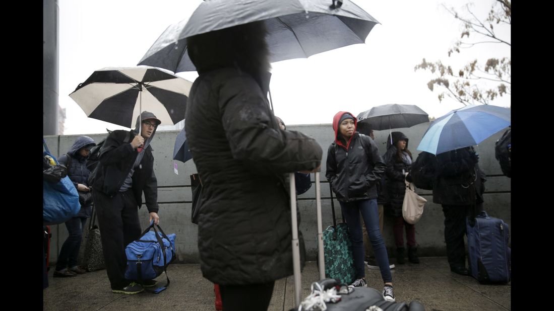 Travelers in New York wait in the rain to board buses heading south on November 26.