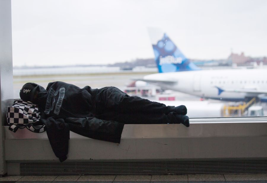 A traveler rests on a bench at New York's LaGuardia Airport on Thursday, November 27. The day before, hundreds of flights were canceled or delayed because of a wintry mix of rain and snow across the East Coast. Most flights are now arriving and departing on schedule.