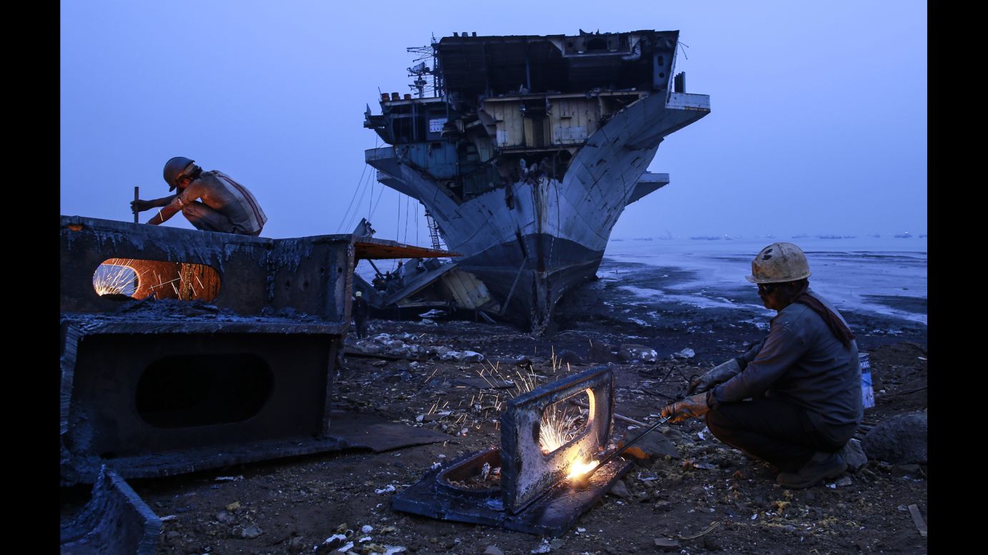 Workers in Mumbai, India, use metal cutters to dismantle parts of the INS Vikrant, India's first aircraft carrier, on Monday, November 24. The ship was decommissioned in 1997.