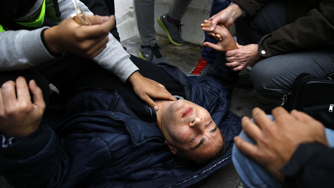 A Syrian refugee is tended to by fellow refugees after he collapsed during a protest in Athens, Greece, on Monday, November 24. The refugees started a hunger strike as they seek food, shelter and asylum in Greece.