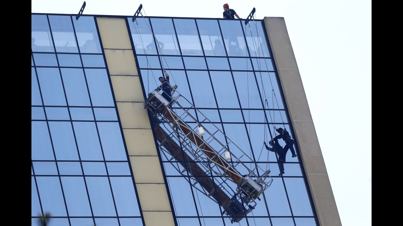Stranded window washers hang on the side of a hotel in Santiago, Chile, on Wednesday, November 26. They were eventually rescued by firefighters.