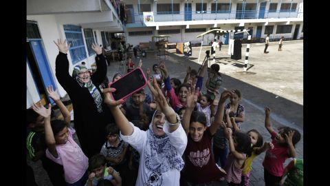 Volunteer Nisreen Shawa uses her phone to take a photo with displaced Palestinian children at a United Nations school in Gaza City on Thursday, August 7.