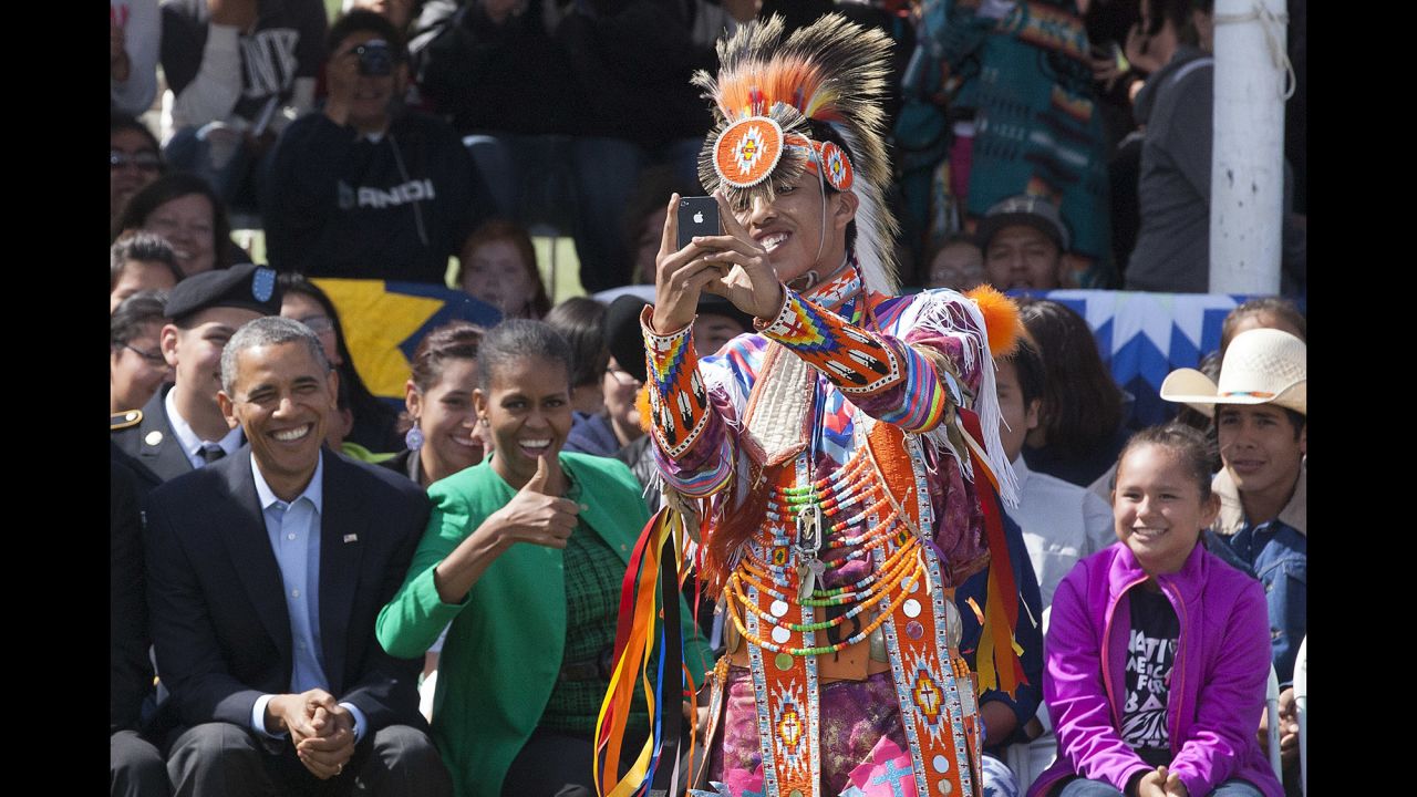A Native American dancer takes a selfie Friday, June 13, in front of U.S. President Barack Obama, left, and first lady Michelle Obama at the Standing Rock Sioux Reservation in Cannon Ball, North Dakota.