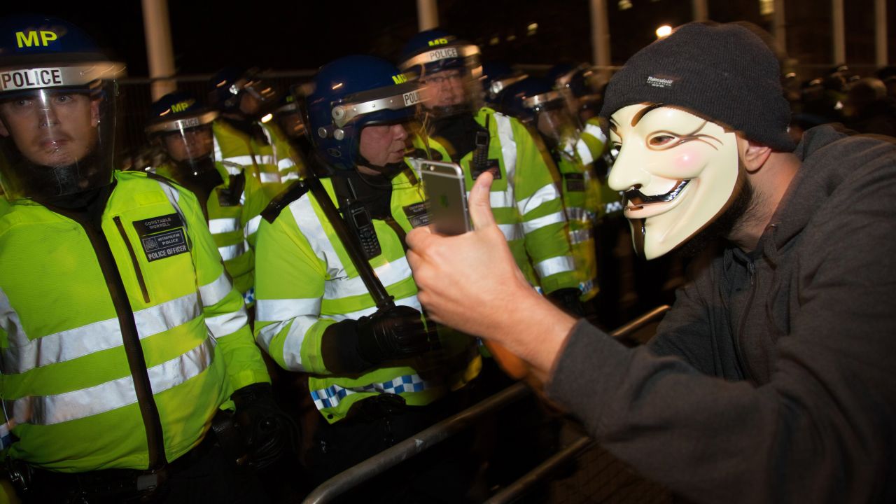 A protester snaps a selfie in front of police during the Million Mask March in London on Wednesday, November 5. The protest, organized by the activist group Anonymous, was said to be against austerity and the infringement of human rights.