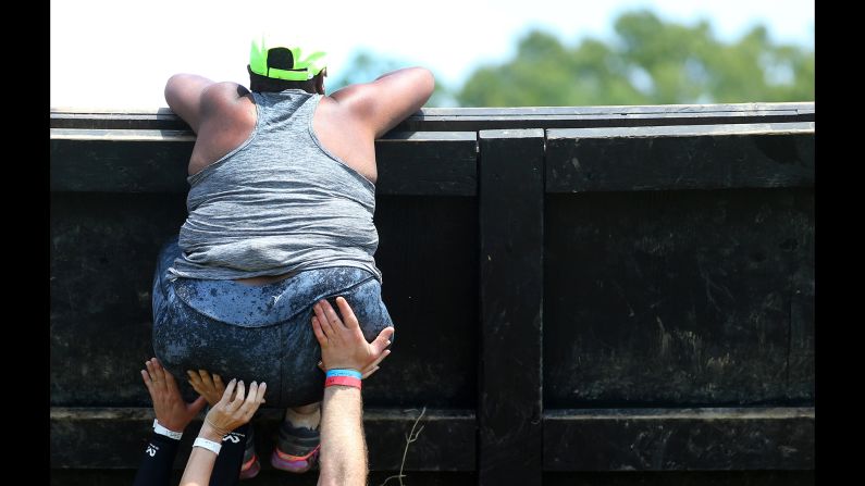 Varios competidores ayudan a una mujer a superar un obstáculo el sábado 28 de junio, durante la Spartan Race en Uncasville, Connecticut.