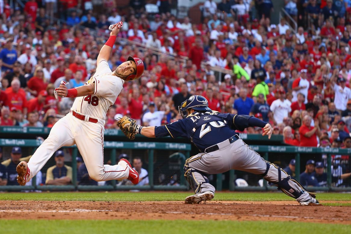 Tony Cruz of the St. Louis Cardinals avoids a tag from Milwaukee catcher Jonathan Lucroy and scores a run Saturday, August 2, in St. Louis.
