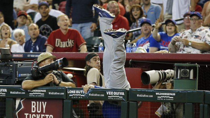 Algunos fotógrafos tratan de evitar a Anthony Rizzo de los Chicago Cubs mientras se lanza de clavado para atrapar una bola fuera de límites, el domingo 20 de julio, en Phoenix.