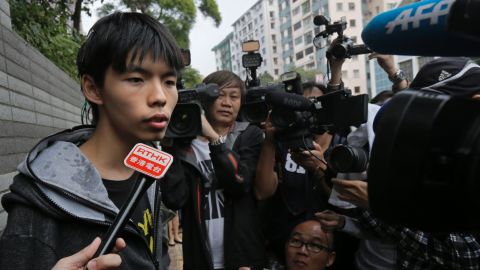 Hong Kong student protest leader Joshua Wong talks to reporters after being pelted with eggs outside a courthouse.