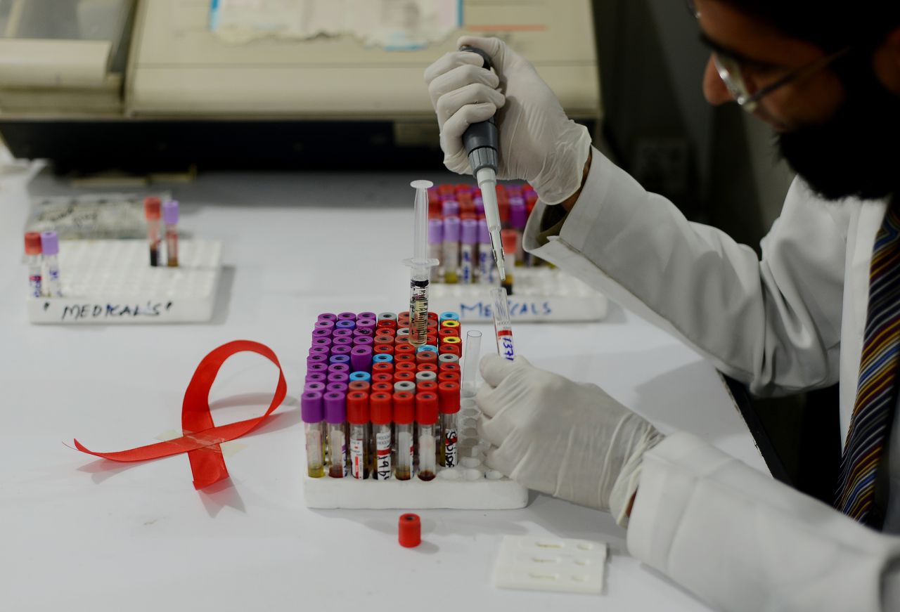 A Pakistani technician takes samples in a laboratory alongside a ribbon promoting World Aids Day in Islamabad on November 30, 2013. 