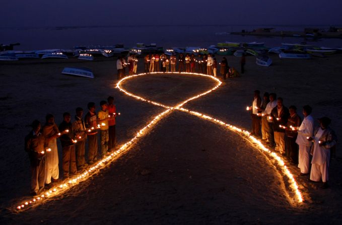 Indian villagers hold oil lamps as they surround a huge AIDS symbol on the beach at Nalsarovar on November 30, 2009, the eve of World Aids Day.