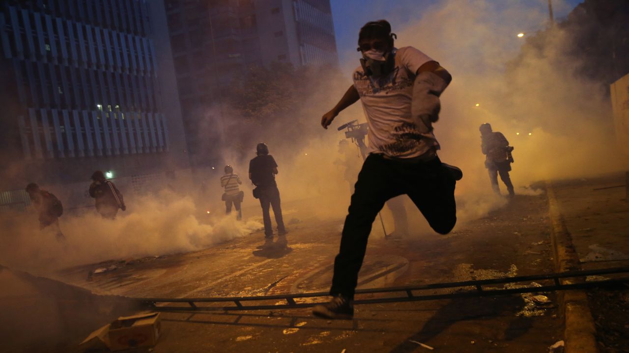 <strong>February 27:</strong> Protesters run from tear gas fired by the Venezuelan National Guard during an anti-government demonstration in Caracas, Venezuela. For months, protesters unhappy with Venezuela's economy and rising crime <a href="http://www.cnn.com/2014/02/18/world/gallery/venezuela-protests/index.html">clashed with security forces.</a>