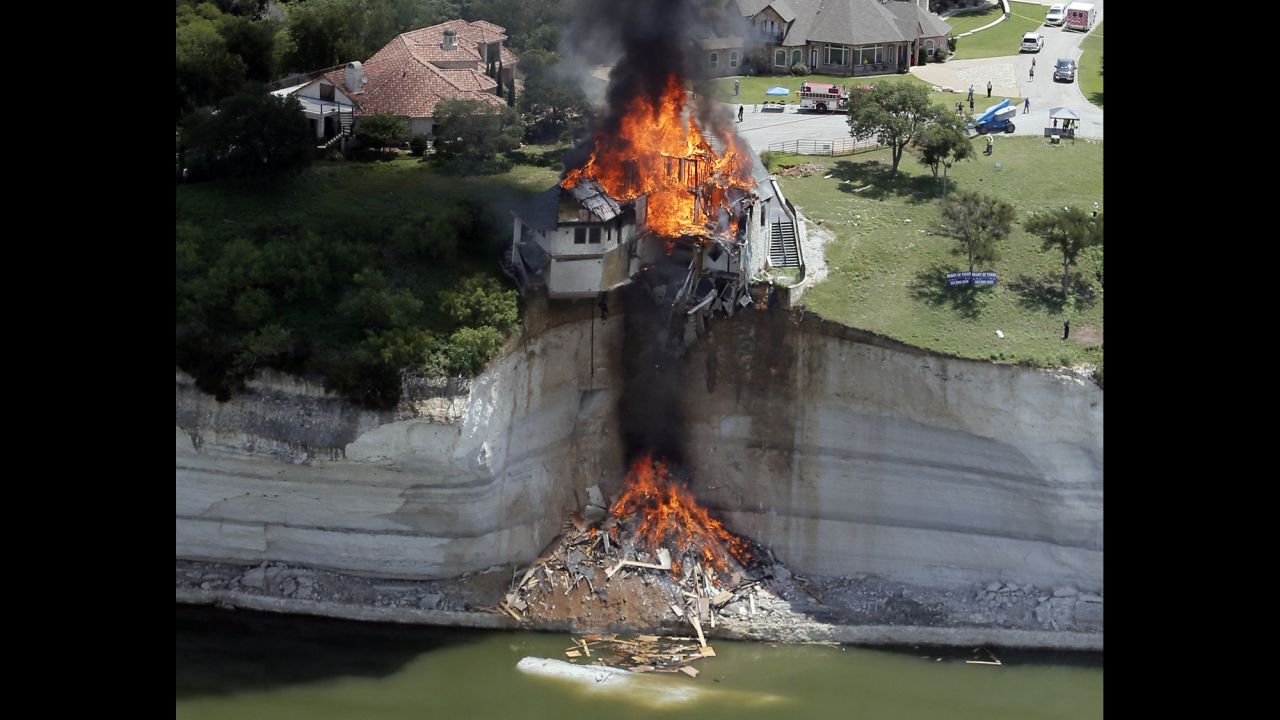 <strong>June 13:</strong> Smoke rises from a house that was deliberately set on fire by building crews near Lake Whitney in Texas. The house was set on fire after part of the ground underneath it collapsed into the lake.