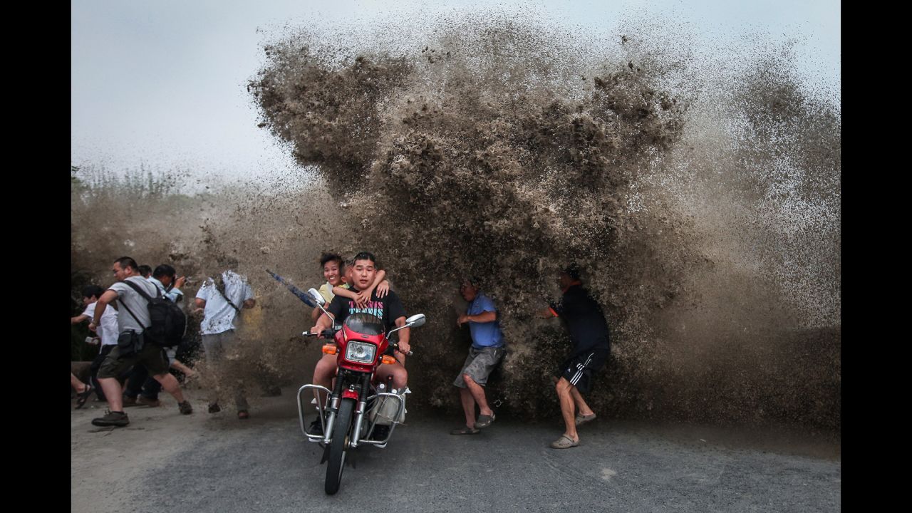 <strong>August 13:</strong> People run as a high wave hits the Qiantang River bank in Hangzhou, China.