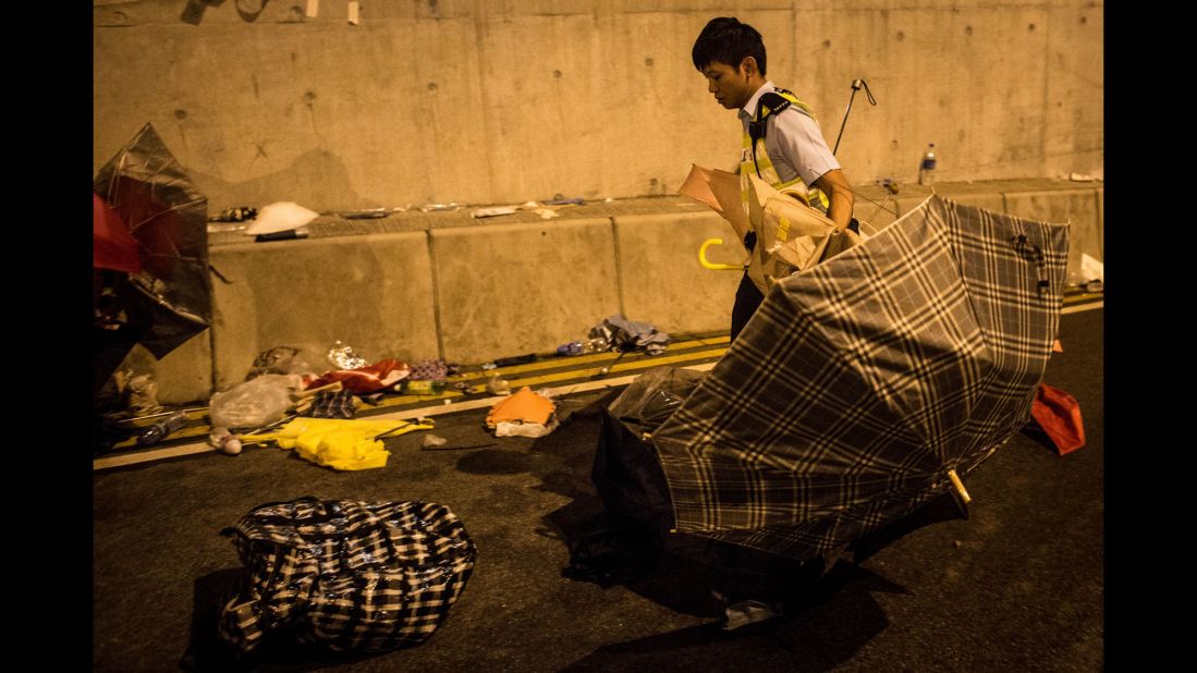 A police officer clears umbrellas from the Lung Wo road tunnel after clashes between protesters and police on December 1.