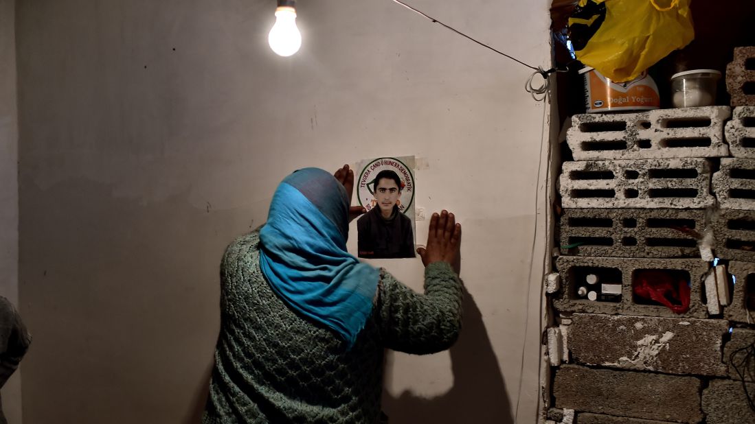 A Syrian Kurdish refugee pins a picture of her son on a wall in Suruc on Tuesday, November 11. She says he died during a battle in Kobani.