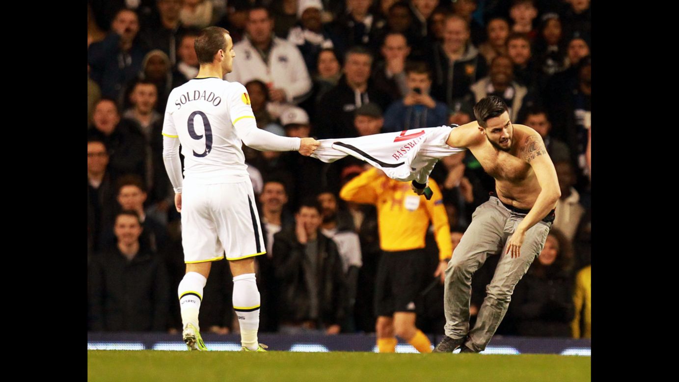 Tottenham's Roberto Soldado holds the jersey of a man who ran onto the field during a Europa League match Thursday, November 27, in London.