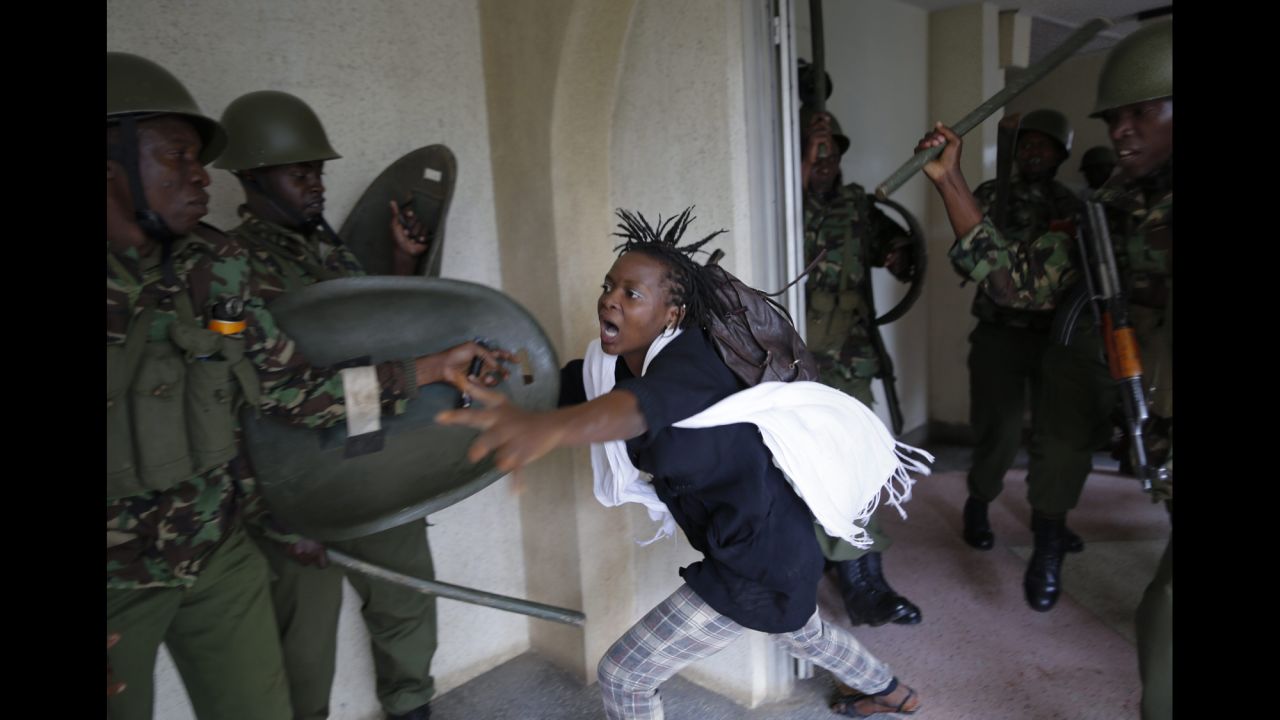 <strong>May 20:</strong> A woman flees as a riot police officer beats her with a baton in Nairobi, Kenya. Hundreds of Nairobi University students took to the streets and faced riot police as they protested against a proposed increase in school fees.