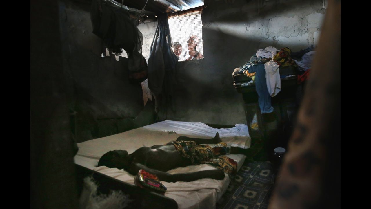 <strong>October 17:</strong> People peer into a bedroom as an Ebola victim's body awaits a burial team in Monrovia, Liberia.