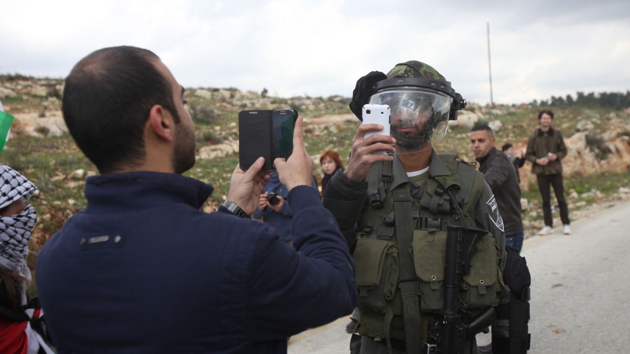 <strong>March 14:</strong> A Palestinian man and a member of Israel's security forces take pictures of each other after a demonstration in the West Bank village of Nabi Saleh.