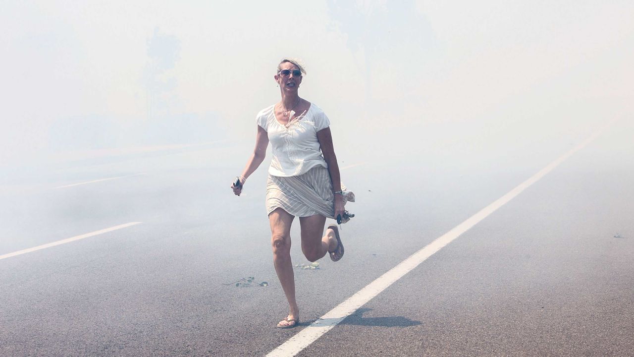 <strong>May 14:</strong> A woman flees a wildfire as it crosses a highway in Carlsbad, California. <a href="http://www.cnn.com/2014/05/13/us/gallery/california-wildfire/index.html">Wildfires forced evacuations in San Diego County</a> after a high-pressure system brought unseasonable heat and gusty winds to the parched state.