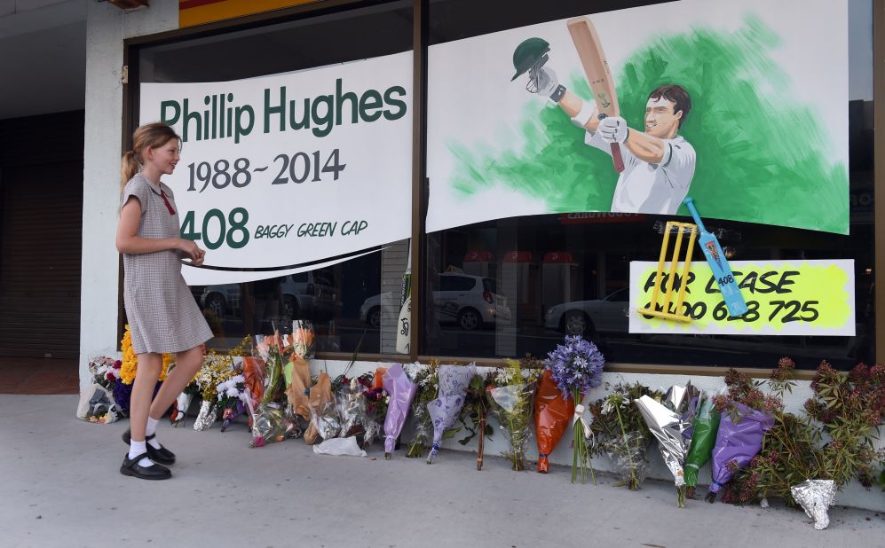 A schoolgirl walks past a tribute to Australian batsman Phil Hughes before his funeral to be held in his home town of Macksville.