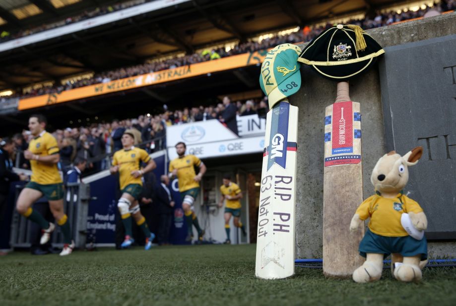 The Australian rugby team run onto the pitch beside a cricket bat and Australian mascot left in tribute to Australian cricketer Phil Hughes at Twickenham Stadium, southwest of London on November 29.