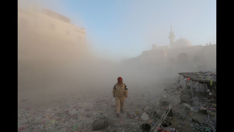 A member of the Syrian Civil Defense walks through a cloud of dust after an alleged air strike by government forces in Aleppo on November 11.