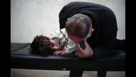 A father cries over his son at a physical therapy center in Eastern al-Ghouta outside Damascus on Thursday, November 6. The boy had his leg tendons cut after he was injured in an airstrike four months before.