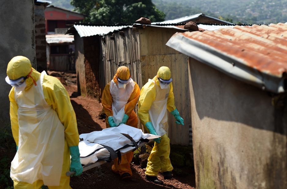 Health workers from Sierra Leone's Red Cross Society Burial Team carry a corpse out of a house in Freetown.  