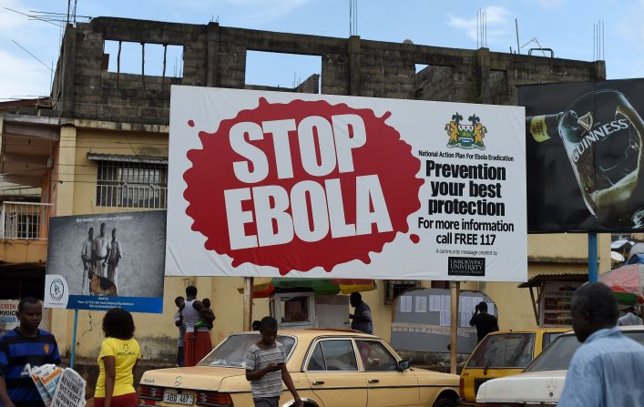 Community awareness was also a priority during the 2014 Ebola outbreak. Pictured, people walk past a billboard with a message about Ebola in Freetown, Sierra Leone.