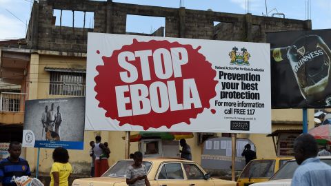 People walk past a billboard with a message about ebola in Freetown