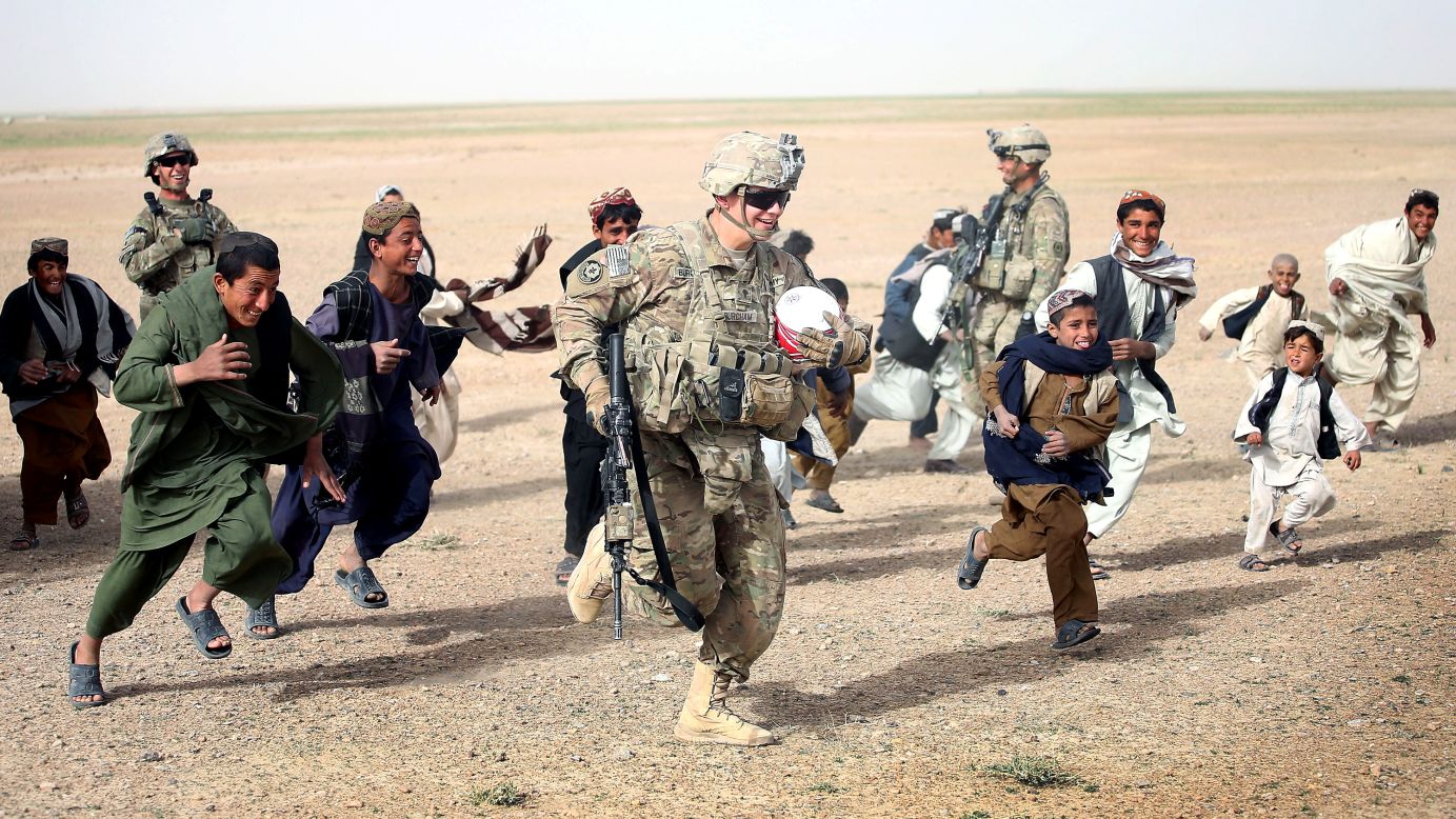 <strong>March 9: </strong>U.S. Army Spc. Taylor Burcham runs with a soccer ball that he gave to children near Kandahar, Afghanistan.