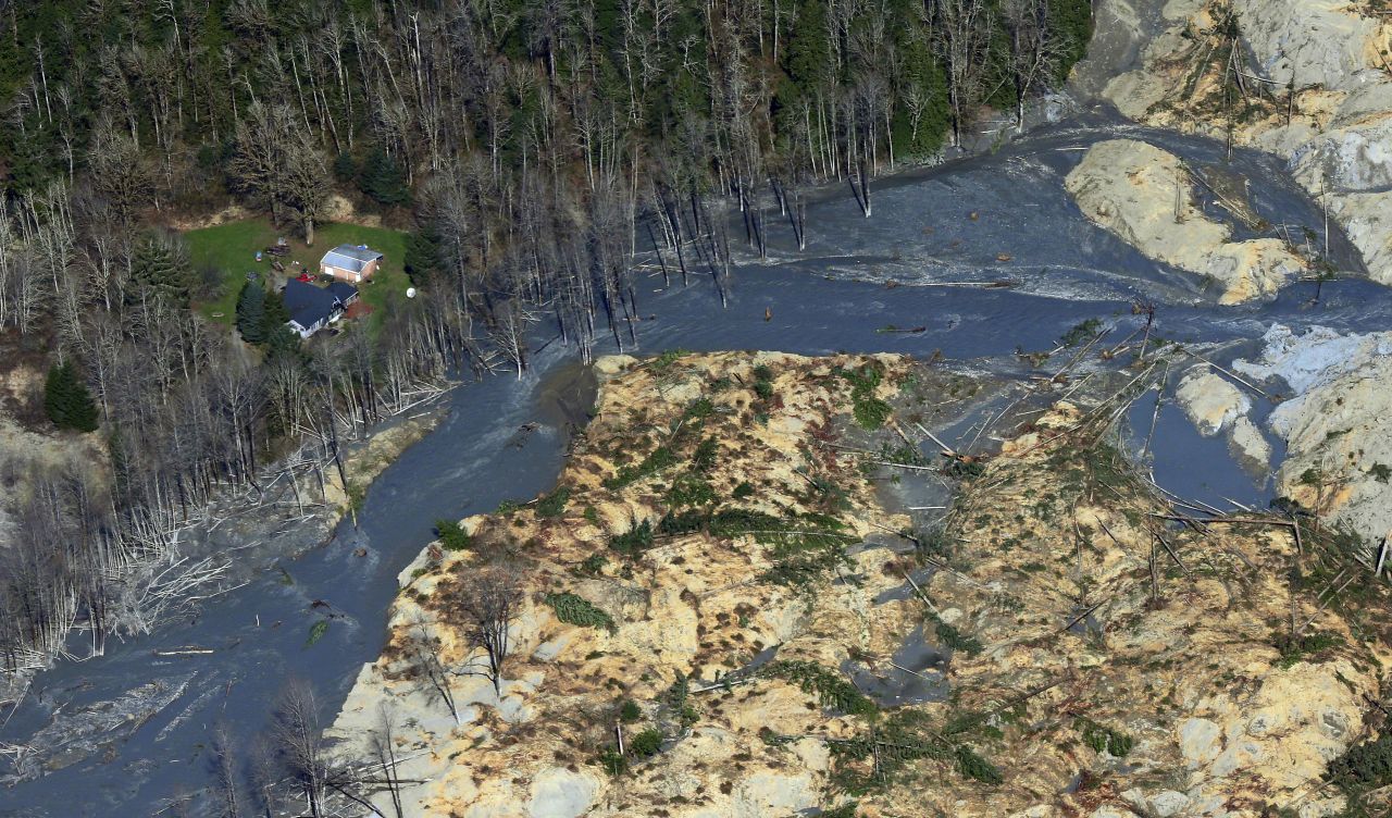 <strong>March 24:</strong> An intact house sits at the edge of <a href="http://www.cnn.com/2014/03/22/us/gallery/washington-landslide/index.html">a massive landslide</a> that devastated Oso, Washington a couple of days before. The landslide crossed the North Fork of the Stillaguamish River, causing multiple deaths and massive damage.