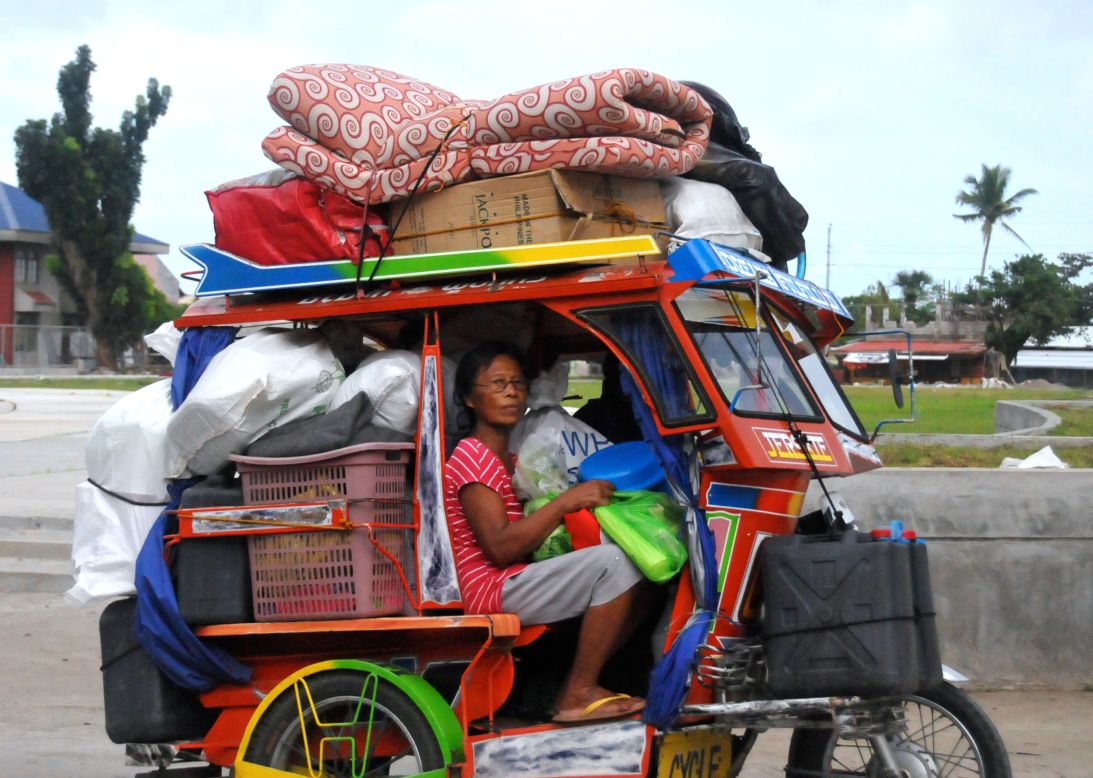 A woman from Tanauan township boards a tuk tuk carrying her belongings in anticipation of Typhoon Hagupit.