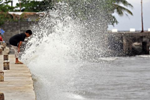 A boy watches as a wave hits the seawall on December 6 along the boulevard in Surigao City, Philippines.
