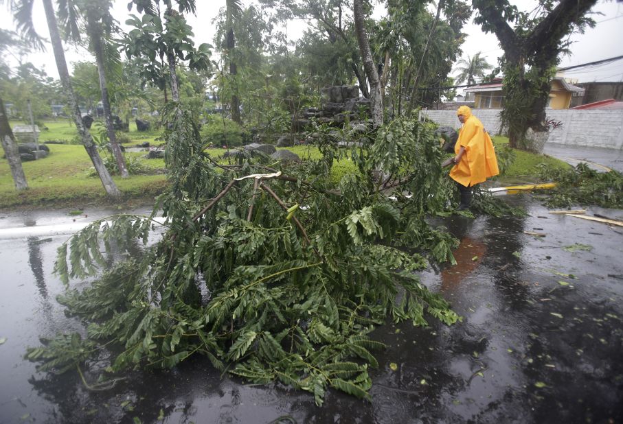 A policeman carries a tree branch that fell due to strong wind  in Legazpi on December 7.